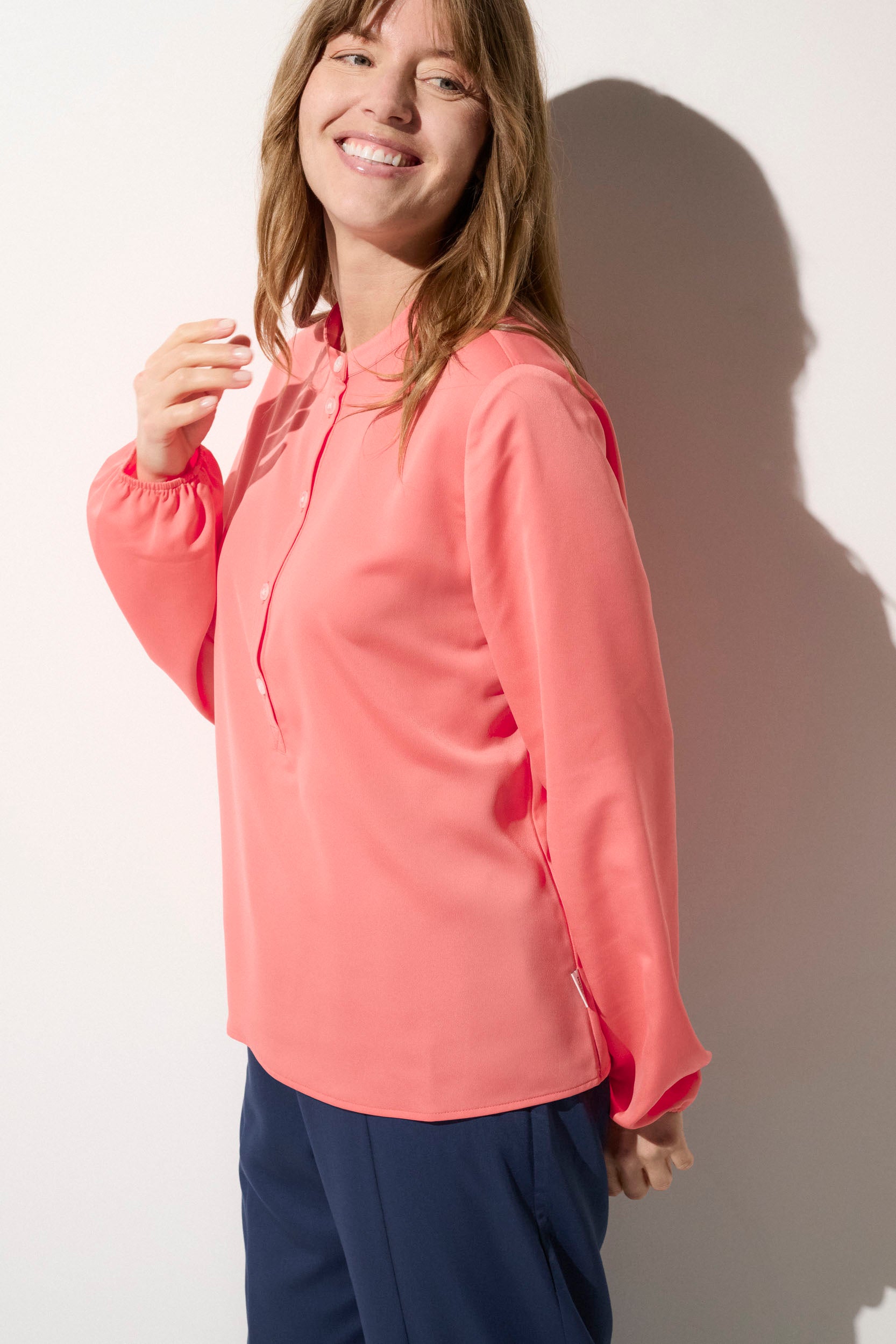 Blouse anti-UV rose UPF50+ pour femme, élégante et légère, idéale pour une promenade en ville ou en bord de mer.