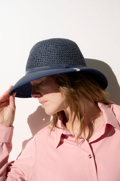 Chapeau anti-UV bleu foncé UPF50+ porté par une femme, idéal pour se protéger du soleil lors des activités extérieures.