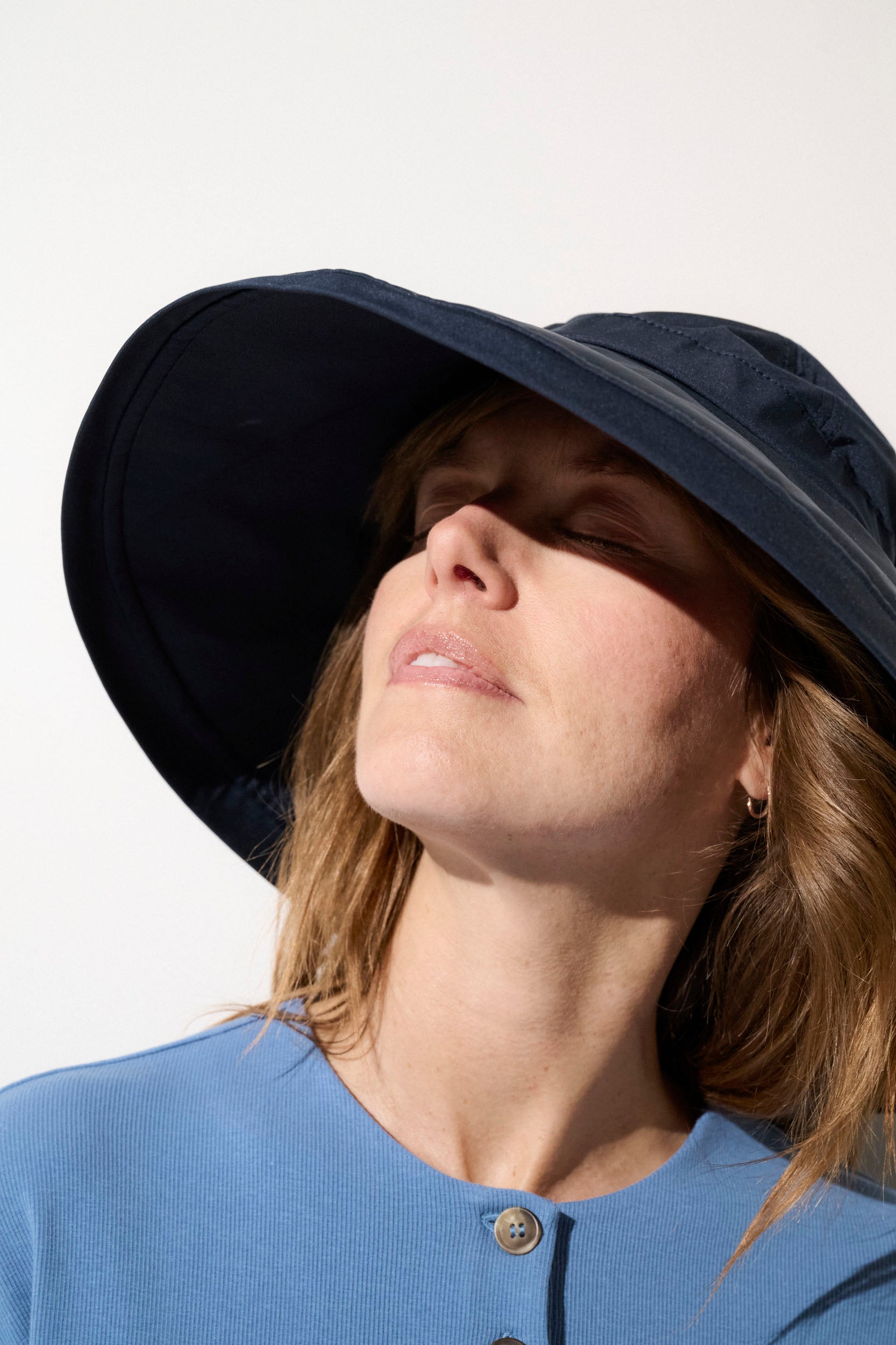 Chapeau anti-UV noir UPF50+ porté par une femme, offrant une protection solaire optimale lors d'activités extérieures.