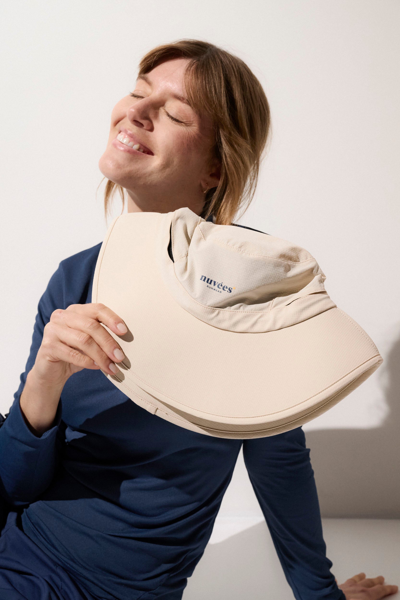 Femme souriante portant un chapeau anti-UV Nuvées, léger et confortable, offrant protection UPF50+.