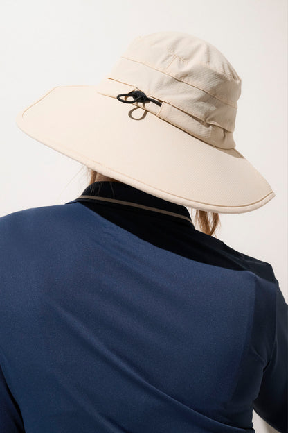 Chapeau anti-UV beige UPF50+ porté par une femme, léger et idéal pour les activités de plein air.