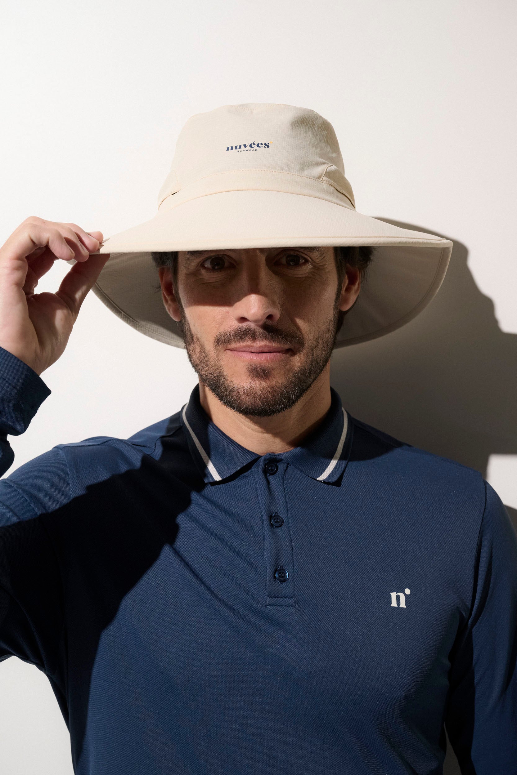 Chapeau anti-UV beige UPF50+ porté par un homme, idéal pour le golf et les activités de plein air.