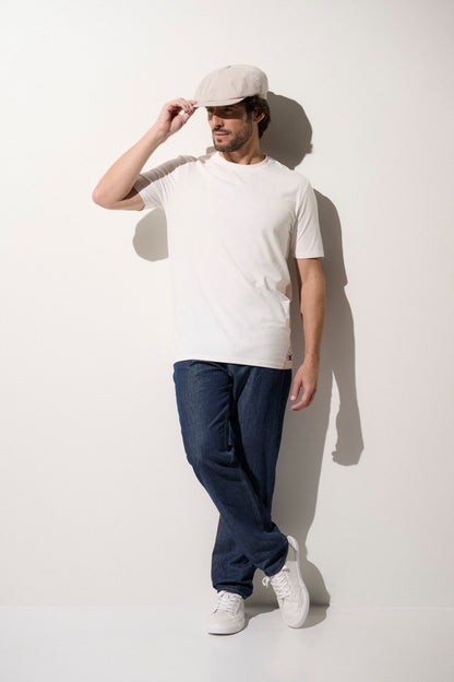 Homme en t-shirt blanc anti-UV UPF50+ et pantalon en denim, prêt pour une sortie décontractée au soleil.