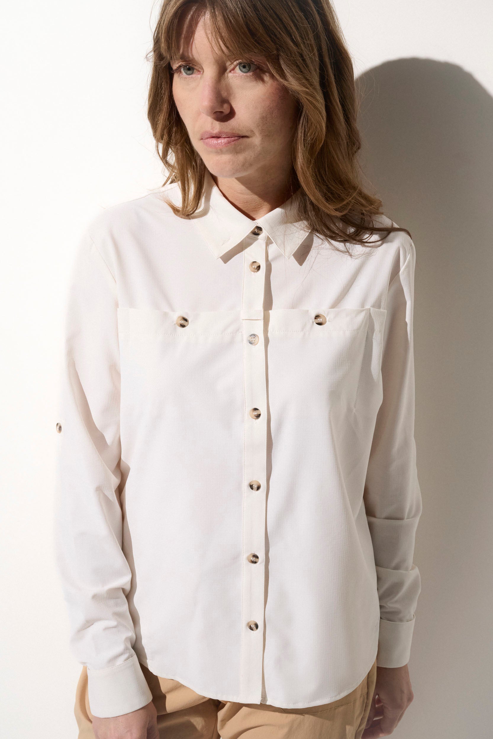 Chemise anti-UV blanche pour femme, légère et élégante, idéale pour protection solaire lors d'activités en extérieur.