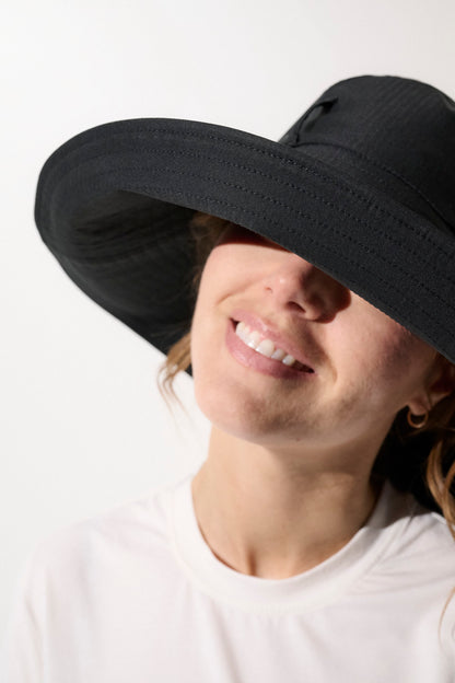 Chapeau anti-UV noir UPF50+ pour femme, à large bord, idéal pour la protection solaire en extérieur.