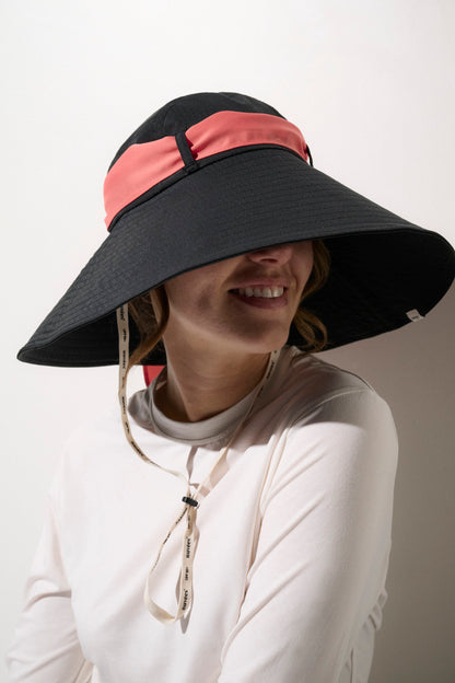 Chapeau anti-UV noir avec bande rose pour femme, offrant une protection solaire efficace et élégante.