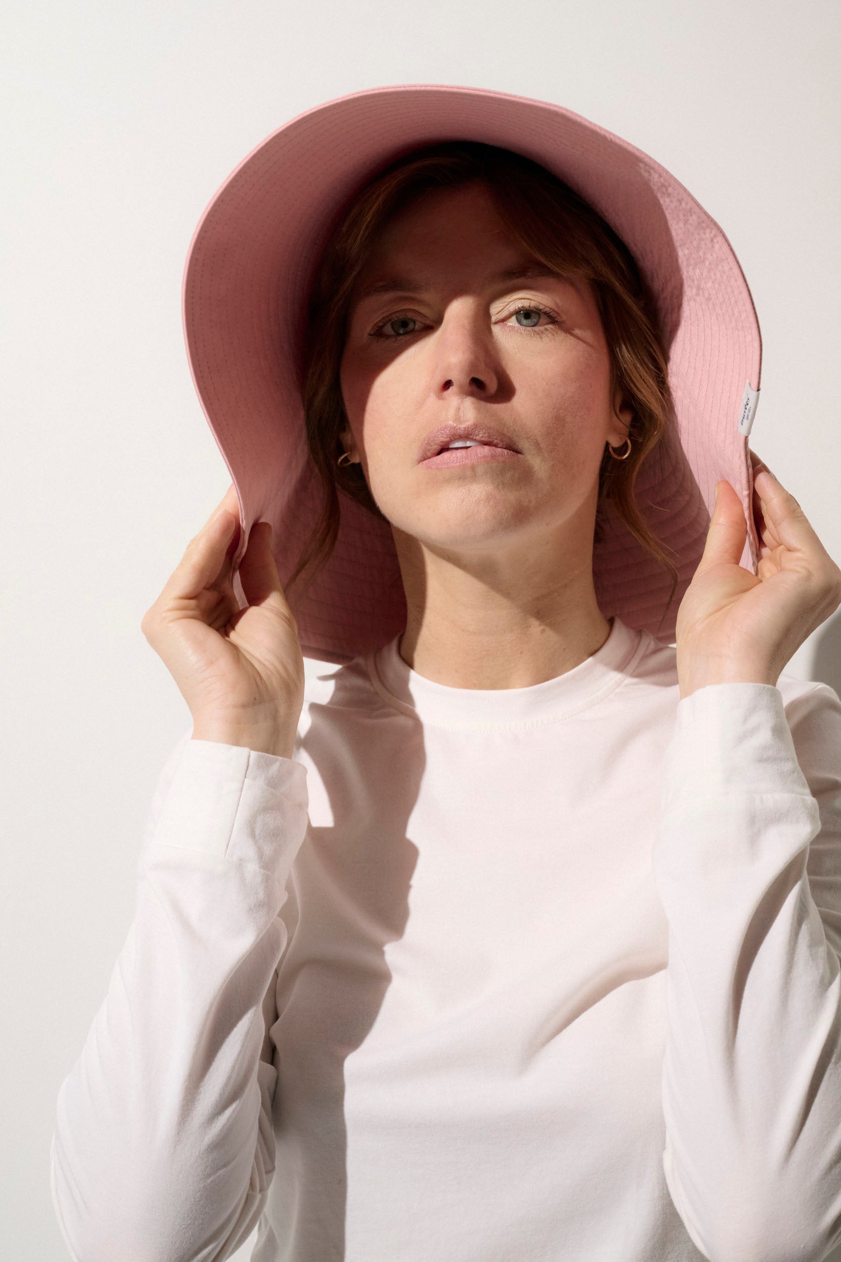 Femme portant un chapeau anti-UV rose UPF50+, idéal pour la protection solaire quotidienne.