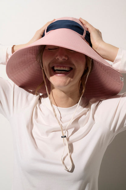 Chapeau anti-UV rose UPF50+ porté par une femme, idéal pour la protection solaire lors d'activités extérieures.