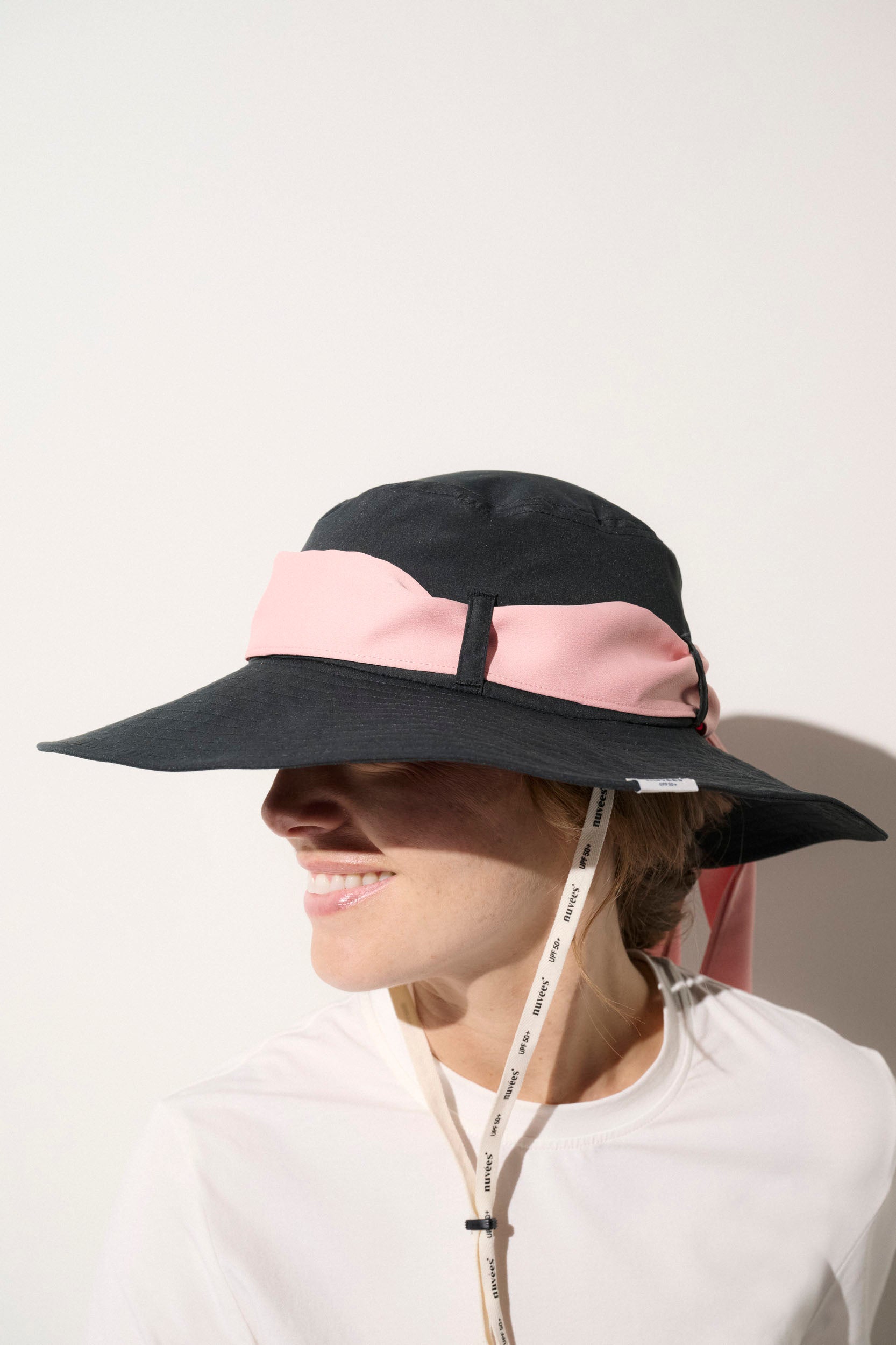 Chapeau anti-UV noir avec ruban rose pour femme, léger et pratique, offrant protection solaire UPF50+.