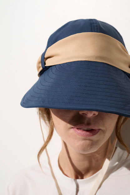 Casquette anti-UV bleue avec bande beige, légère et confortable, idéale pour une protection solaire lors d'activités en extérieur.