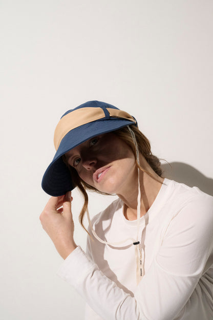 Casquette visière anti-UV bleu marine et beige, légère, pour femme, offrant une protection solaire UPF50+ idéale pour les activités en plein air.