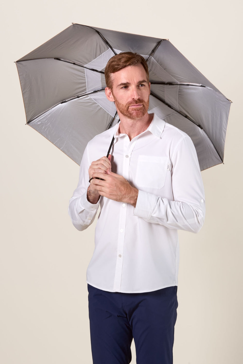 Homme portant une chemise blanche sous une ombrelle anti-UV UPF50+, offrant protection solaire élégante.