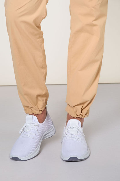 Pantalon anti-UV beige pour homme, confort et protection solaire, associé à des baskets blanches légères.