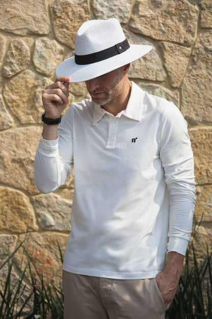 Polo anti-UV blanc à manches longues pour homme, certifié UPF 50+, porté avec un chapeau dans un environnement extérieur.