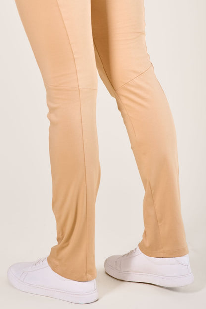 Pantalon anti-UV Café Glacé pour femme, léger et confortable, offrant une protection solaire UPF 50+, porté avec des chaussures blanches.