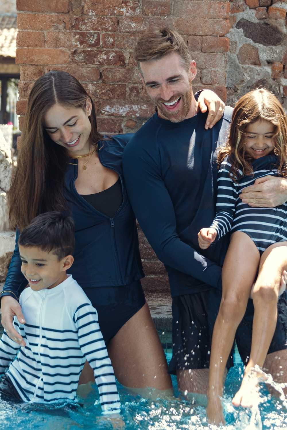 Famille en vêtements de bain anti-UV, homme et femme en maillots, enfants s'amusant dans la piscine, protection UPF 50+.